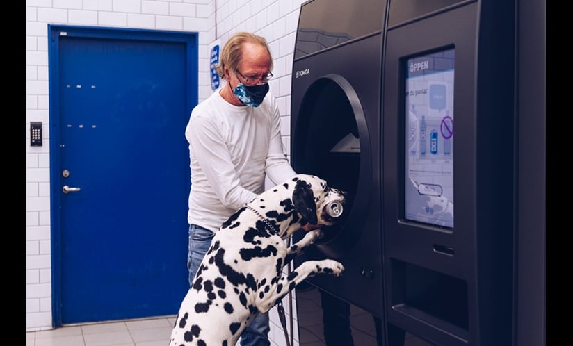 Photo de Gazton, le chien recycleur, mettant un contenant dans la machine
