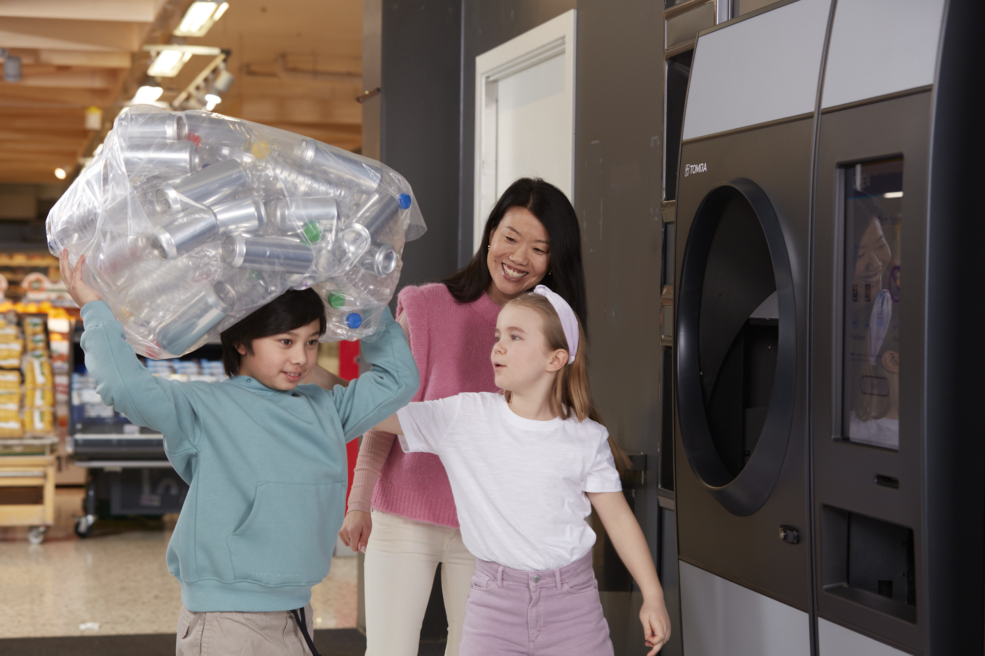 Imagen de niños y adultos reciclando en una máquina de vending inverso