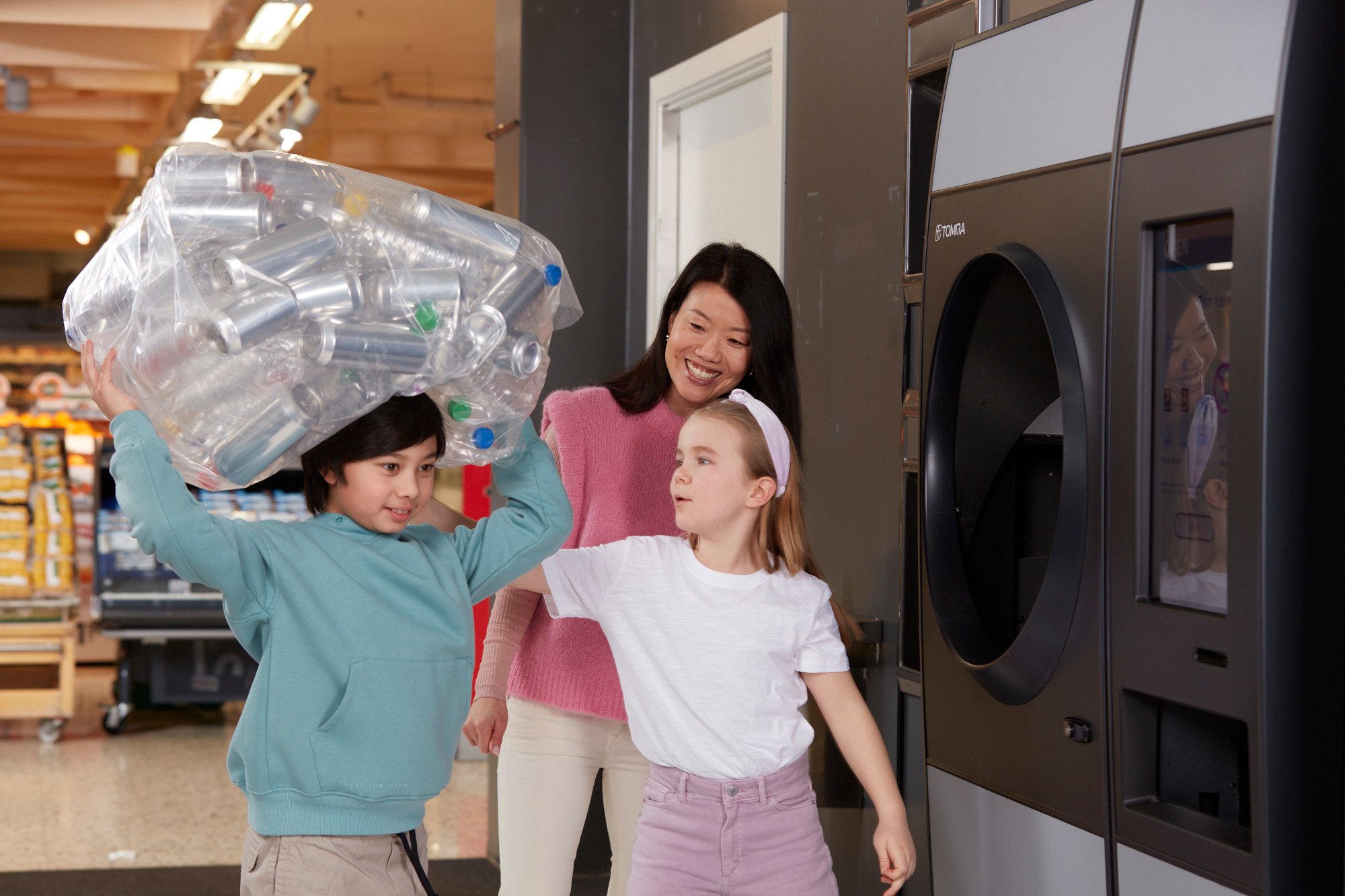 Photo d'enfants et d'une adulte recyclant devant un automate de déconsigne