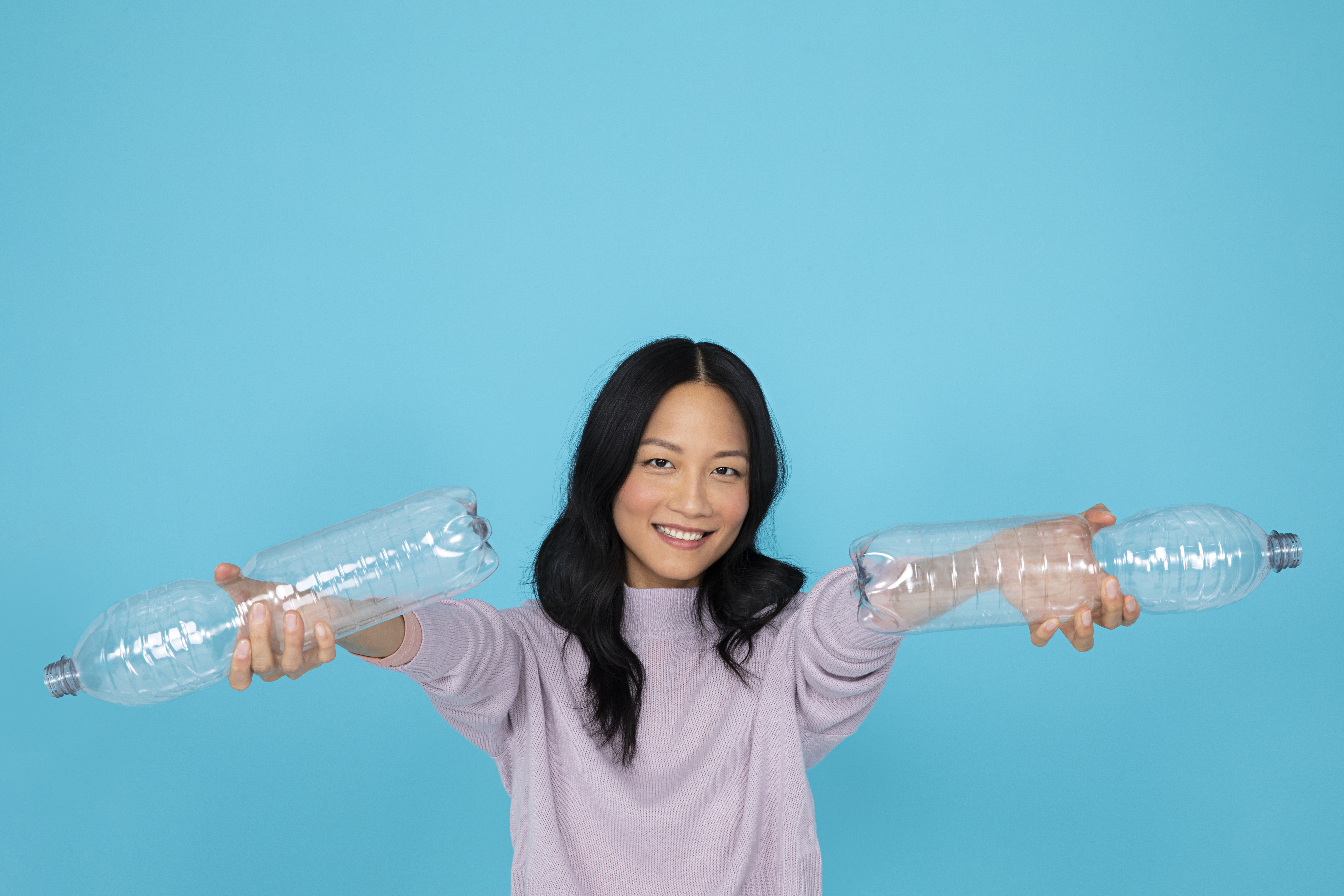 Niña asiática sosteniendo botellas de PET