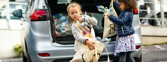 Imagen de niños cogiendo envases del maletero de un coche