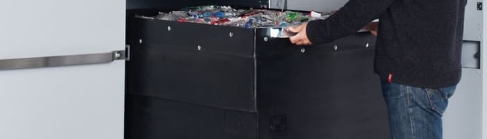mand tømmer beholder på en TOMRA T90 flaskeautomat