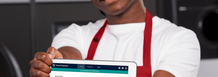 Smilende butiksmedarbejder, der viser en tabletskærm med et digitalt værktøj fra TOMRA 