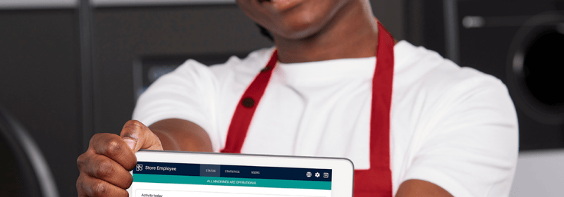 Smilende butiksmedarbejder, der viser en tabletskærm med et digitalt værktøj fra TOMRA 