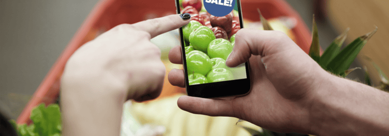 Ekranında satışlar yazan bir işaret bulunan telefon tutan kişi