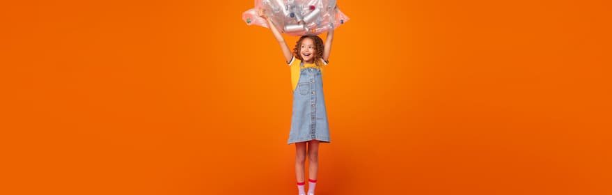 Retrato de una niña con una bolsa llena de botellas sobre un fondo naranja