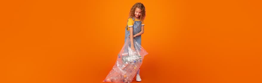 Portræt af en pige, der holder en taske fuld af emballage på en orange baggrund