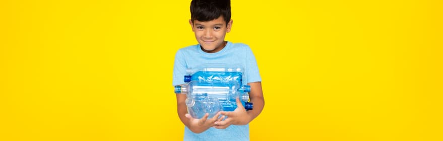 Pojke mot gul bakgrund som håller PET-flaskor