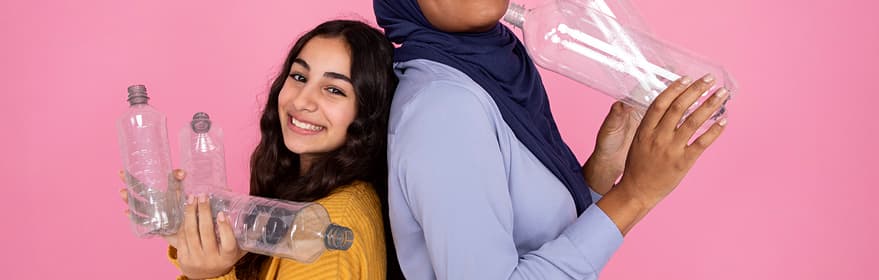 Una chica con hijab y una chica india sosteniendo botellas de PET