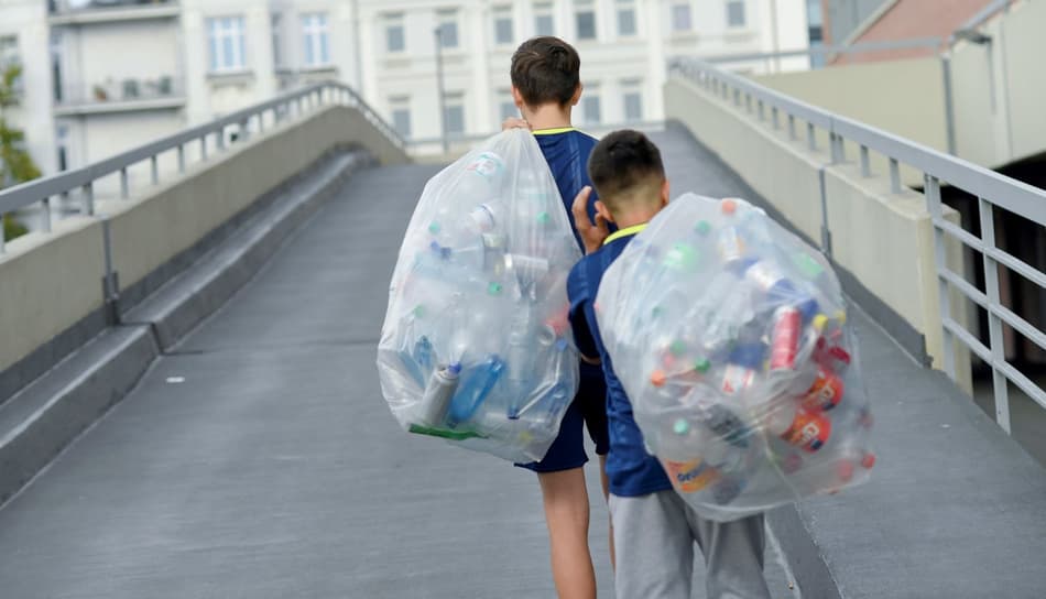 Imagen de niños transportando bolsas de envases de bebidas