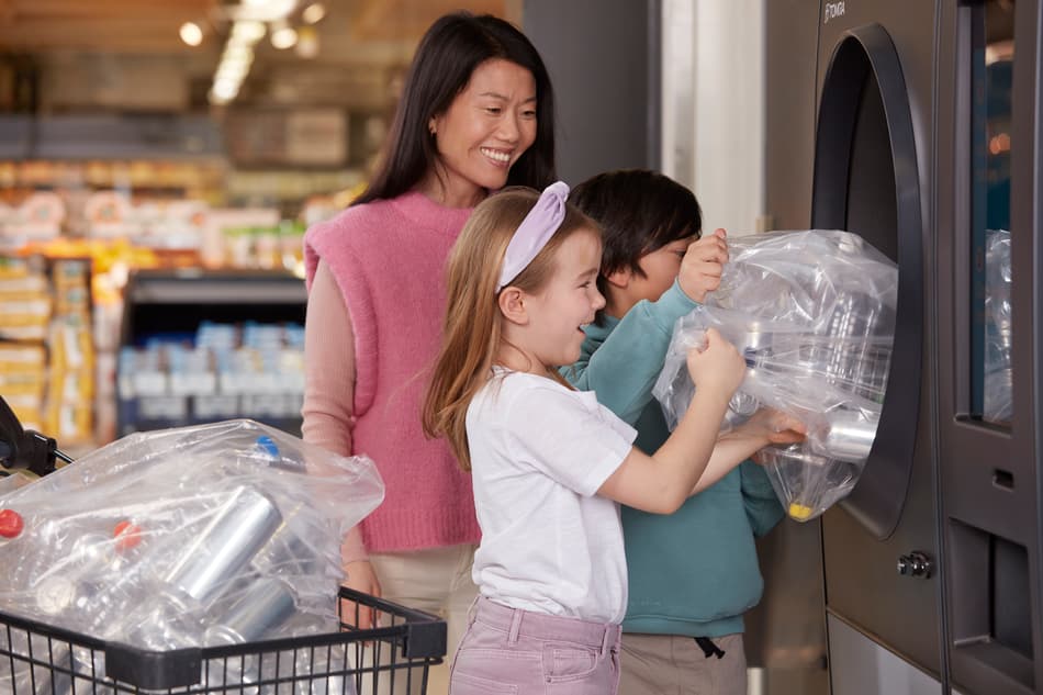 Una señora y sus hijos colocan envases vacíos en una máquina de vending inverso de TOMRA