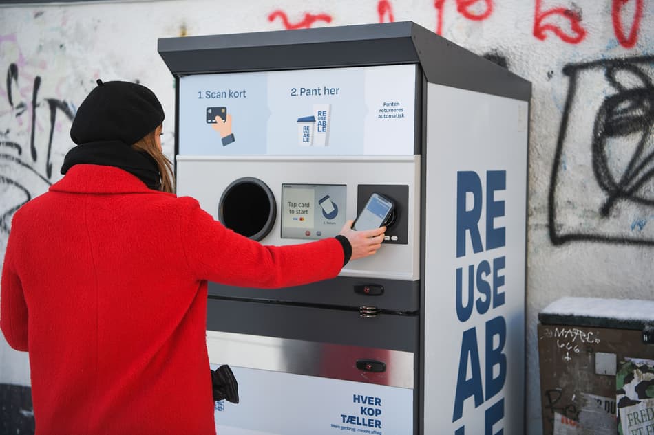 Un consommateur retourne un gobelet réutilisable à un point de collecte TOMRA à Aarhus, au Danemark