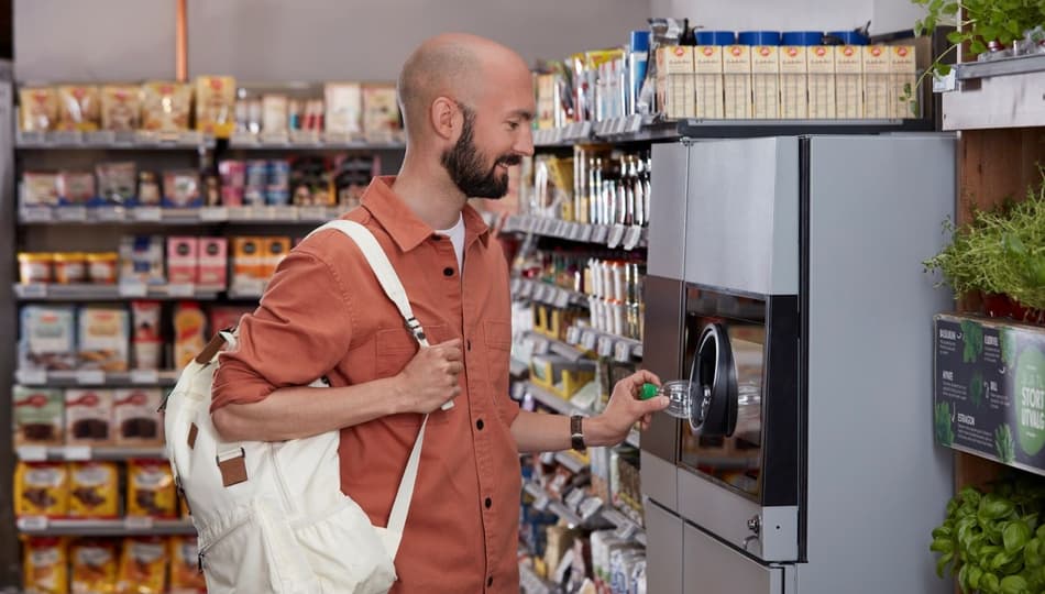 Imagen de un hombre devolviendo latas a una máquina de vending inverso