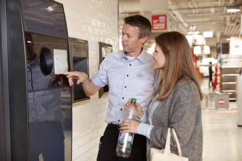 image of a retailer assisting consumer on using a reverse vending machine