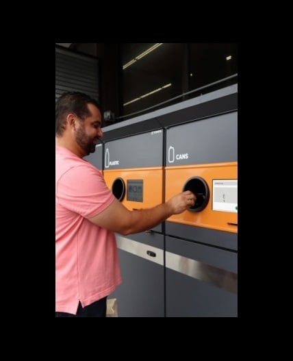 image of a man using a reverse vending machine