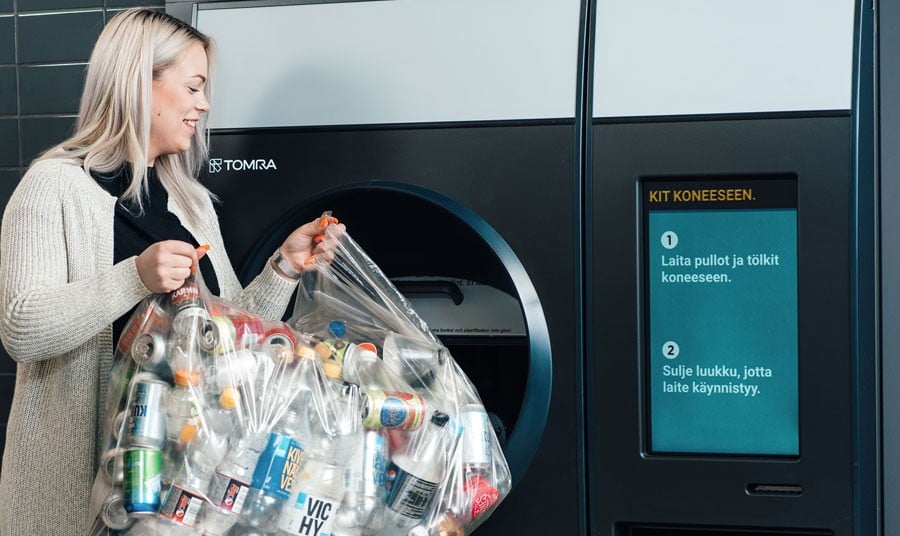 lady feeding bottles into a reverse vending machine