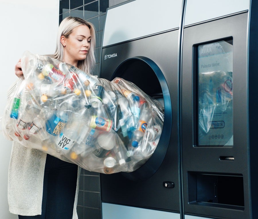 image of a woman pouring bottles into a reverse vending machine