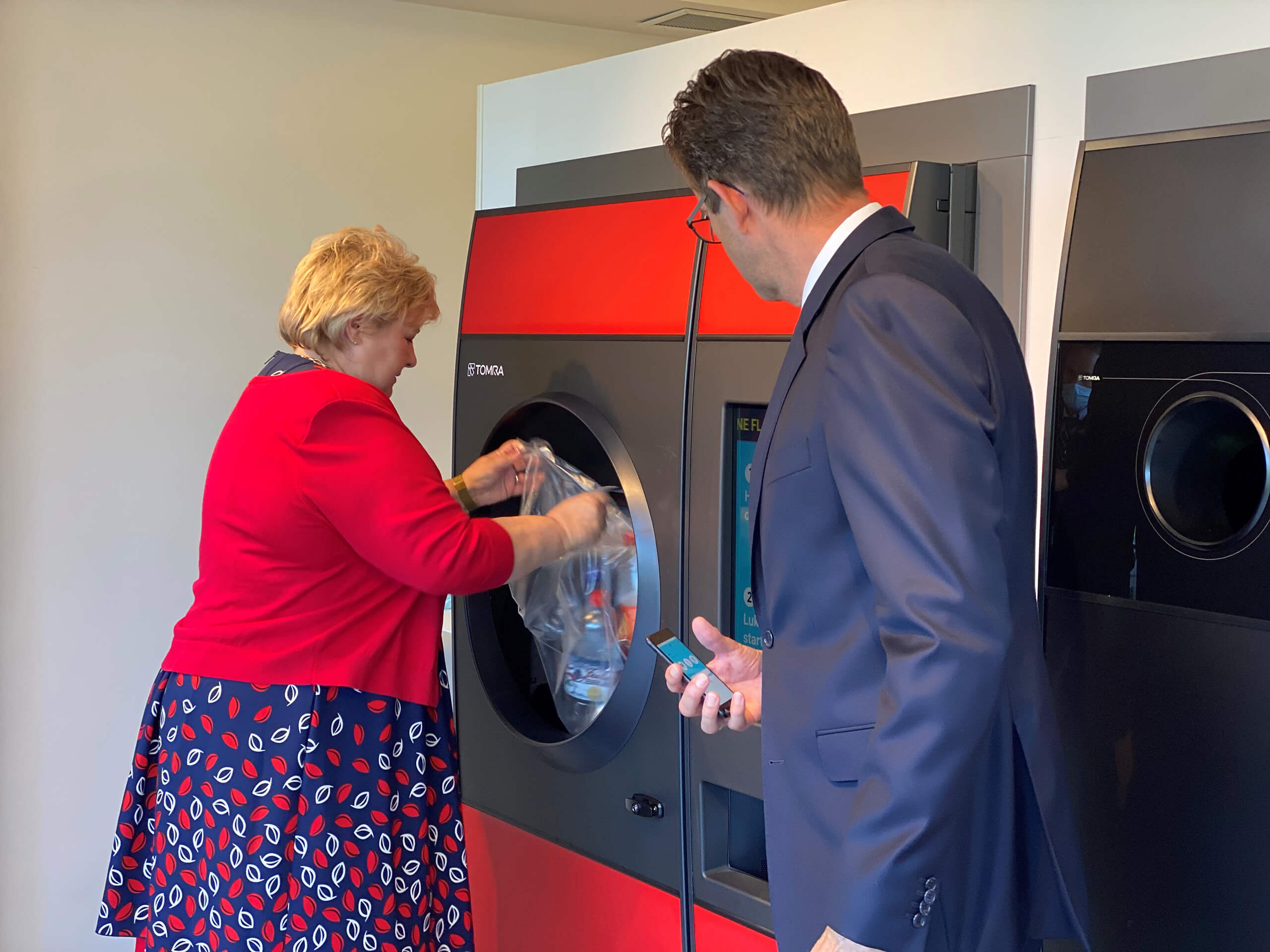 image of former prime minister Erna Solberg trying reverse vending machine
