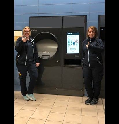 image of two coop staff standing beside a reverse vending machine 