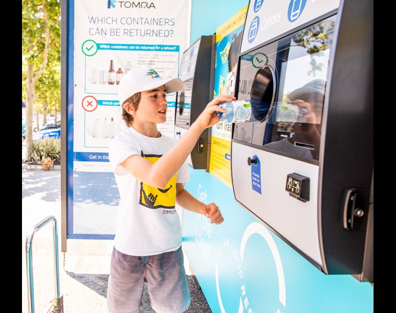 a boy feeding a bottle to reverse vending machine