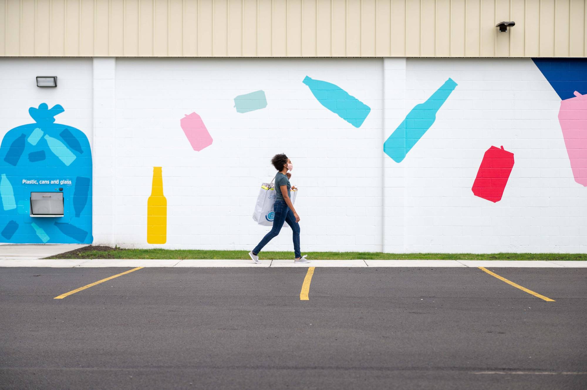 Woman walking with bag of recyclables outside recycling centre
