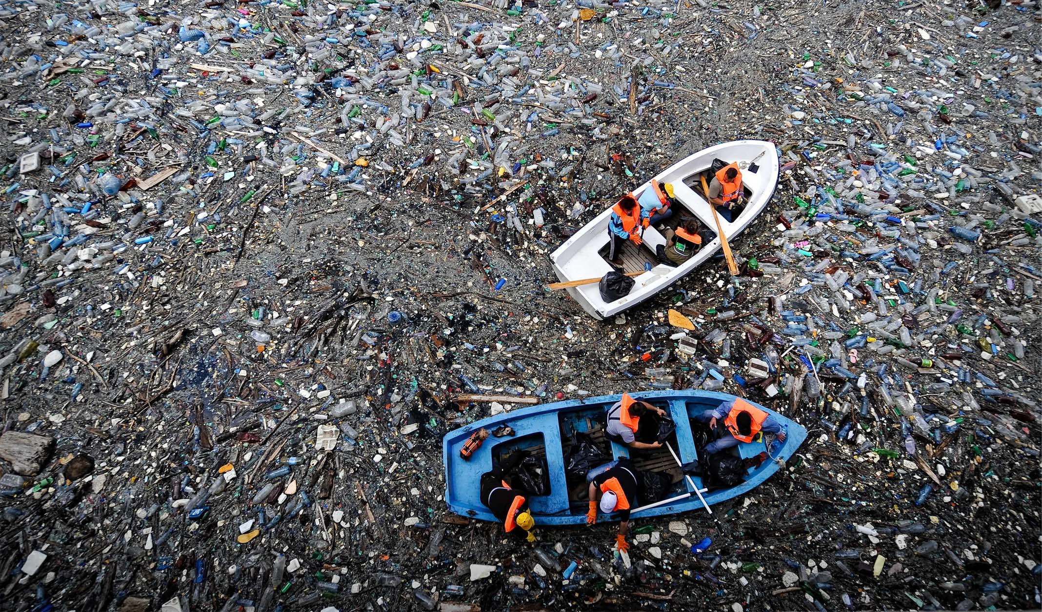 Boat floating in an ocean full of litter