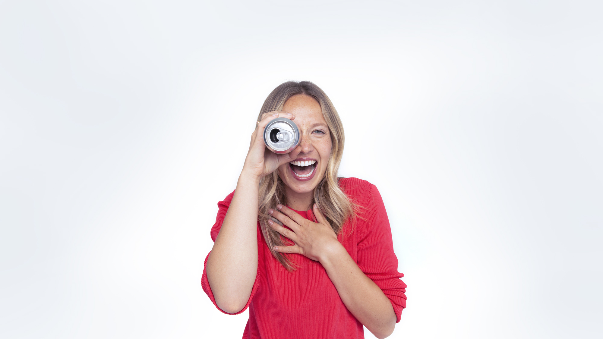 Smiling woman holding a can up to her eye