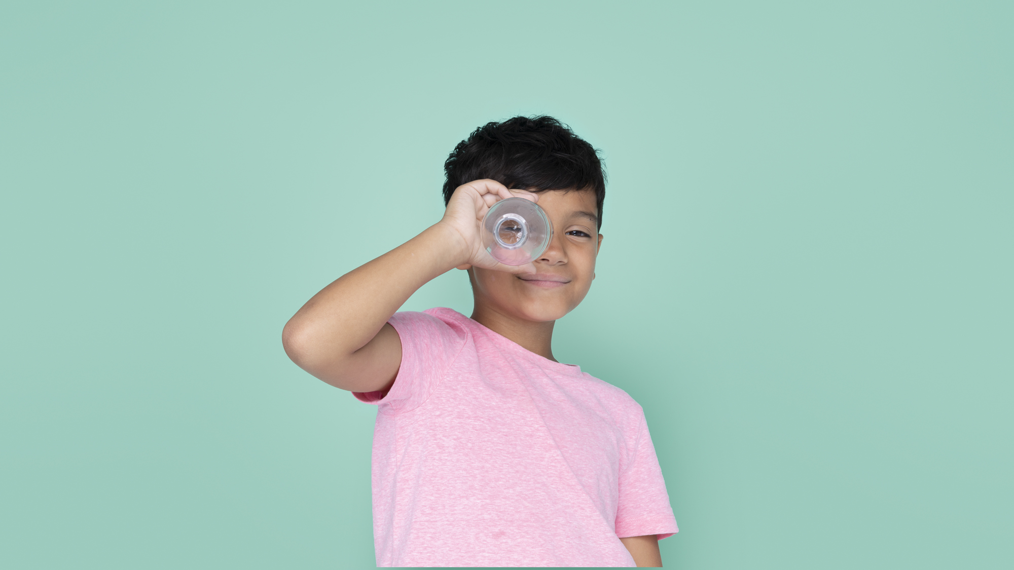 Smiling boy using a bottle as a telescope