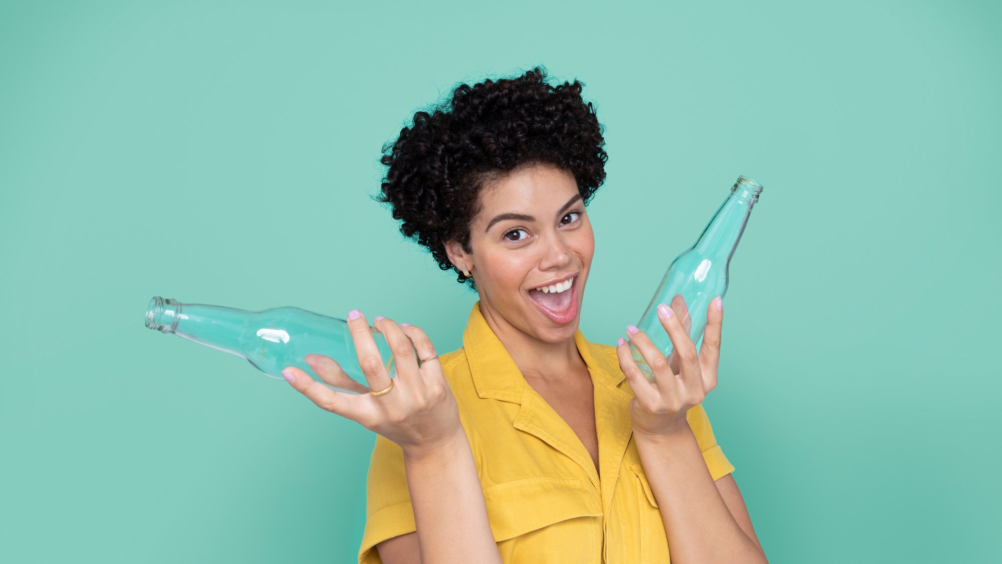 Lächelnde Frau hält zwei Glasflaschen hoch 