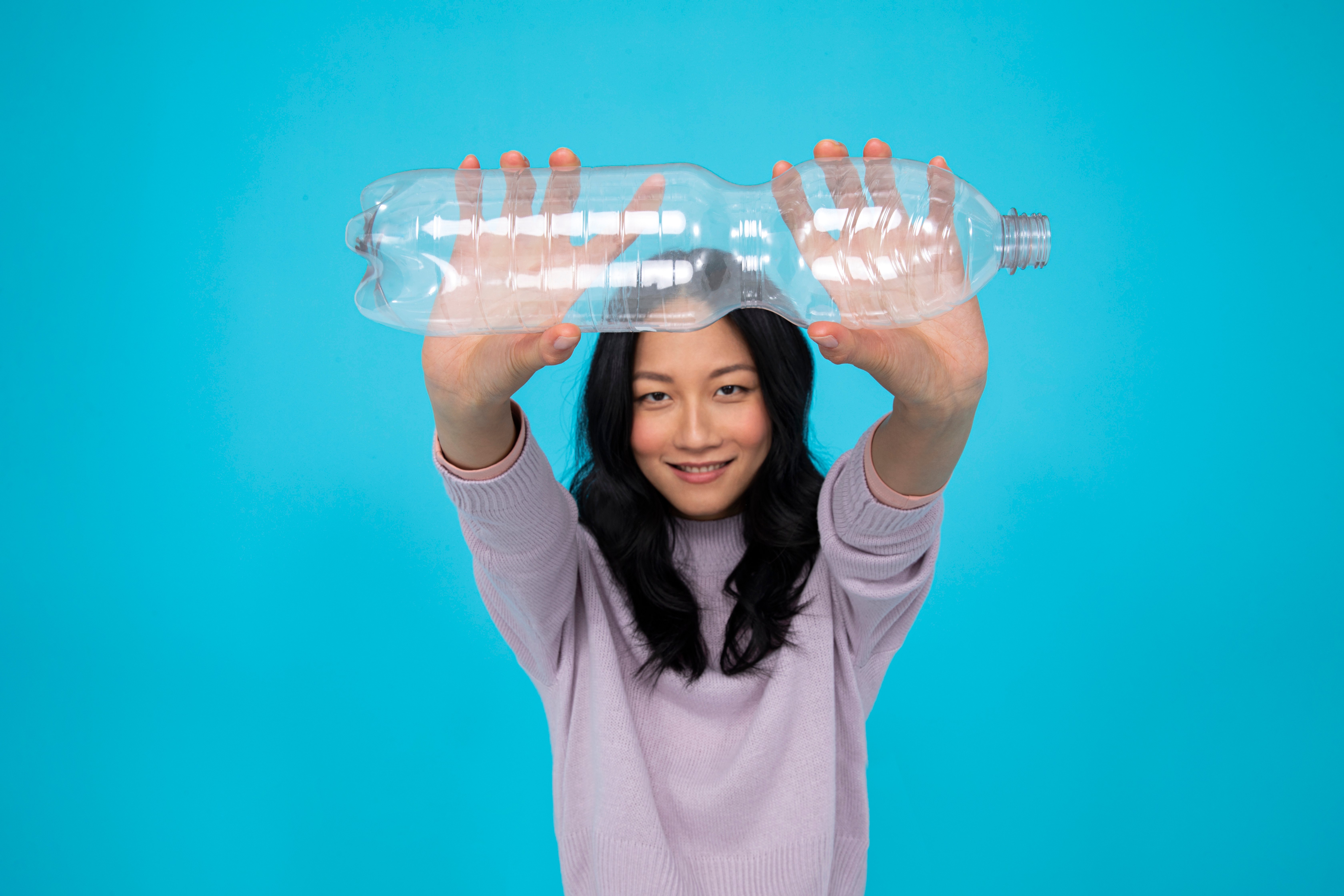 Asian girl holding one PET bottle and smiling