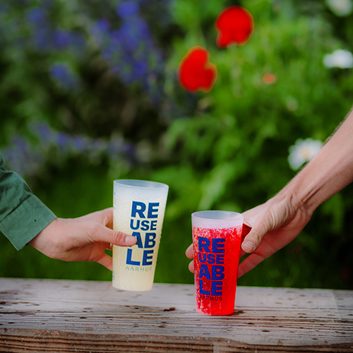 Two people picking up two tall REUSEABLE cold drink cups