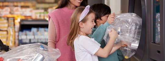A lady and her children placing empty containers into a TOMRA reverse vending machine
