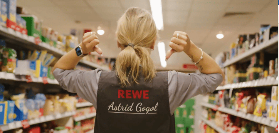 Astrid Gogol pointing at REWE logo