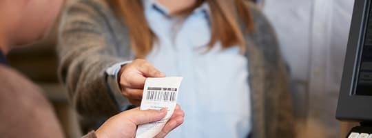 Smiling woman handing over a voucher from a deposit return machine