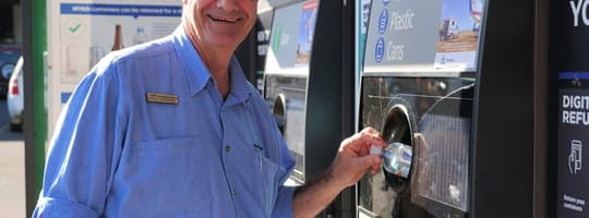 Man recycling bottle in reverse vending machine