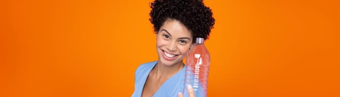 Girl orange background holding PET bottle