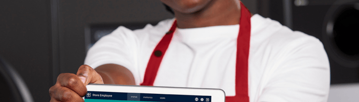 Empleado de tienda sonriendo y mostrando la pantalla de una tableta donde se ve una herramienta digital de TOMRA 