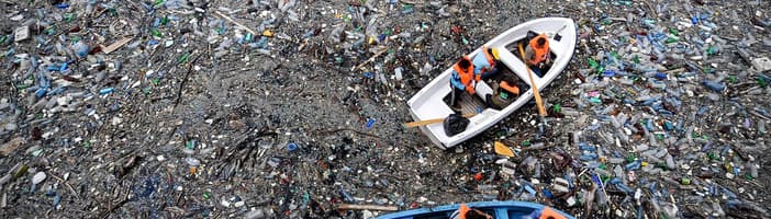 Image of boats moving through plastic pollution