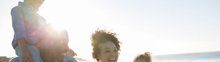 Young family walking along a beach and smiling