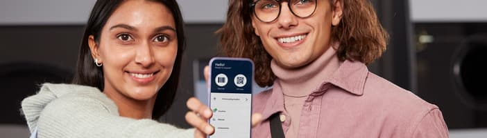 Young couple smiling and holding a phone where you can see myTOMRA screen