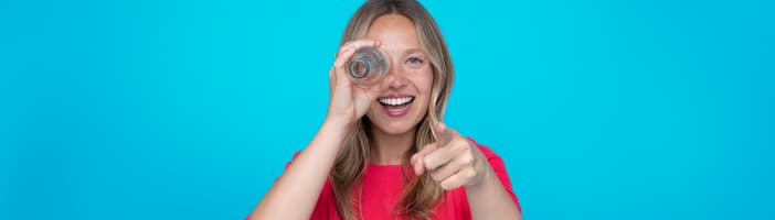 Blondes Mädchen vor rosafarbenem Hintergrund, das auf etwas zeigt