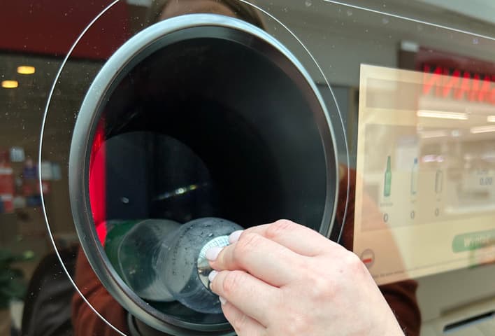 Persona introduciendo una botella de plástico en una máquina de vending inverso