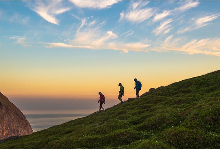Three people walking on mountain ridge