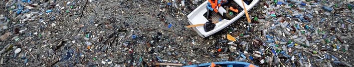 Boat floating in an ocean full of litter