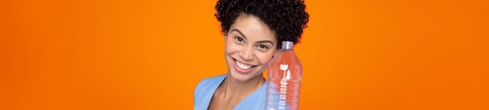 Girl orange background holding PET bottle