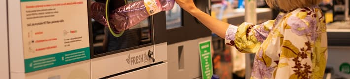 Woman feeding bottles in the reverse vending machine