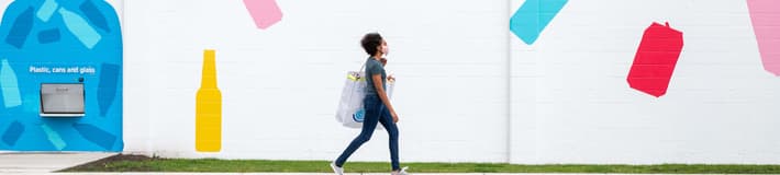 Woman walking with bag of recyclables outside recycling centre