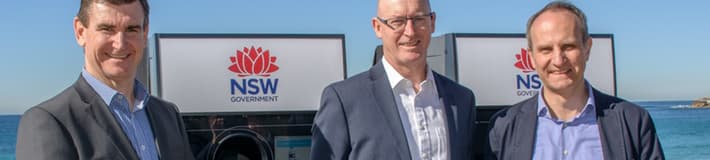 Three men in suits in front of New South Wales reverse vending machines