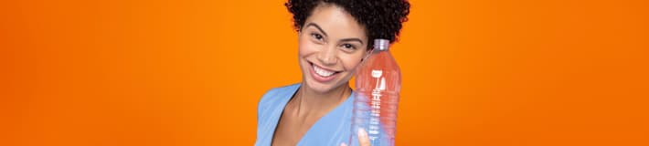 Mädchen vor orangefarbenem Hintergrund, das eine PET-Flasche hält