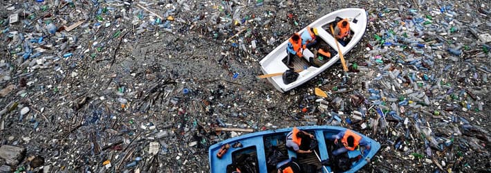 Boat floating in an ocean full of litter